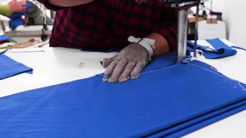 Female worker with an electric knife cutting cloth in a textile factory. Textile industy. video