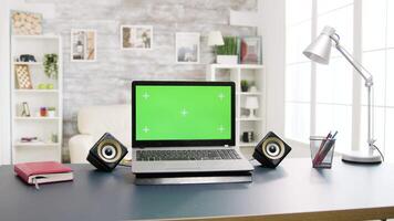 moderno ordenador portátil con verde pantalla acostado en el mesa en brillante vivo espacio. no chico en el Disparo video