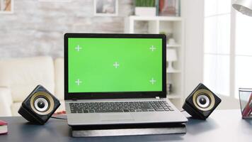 Chroma isolated laptop with green screen on the table in bright and modern flat. Zoom in parallax type footage with nobody in the room video