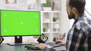 Zoom in parallax footage of young man working on PC with green screen in bright living room video