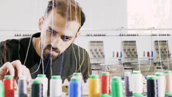 Man in a fabric factory checking the cotton sewing machinery. Sewing industry. Industrial interior. video