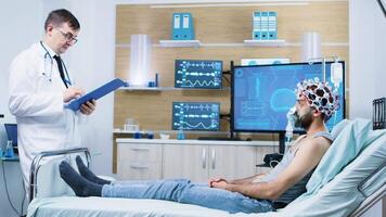 Doctor in brain activity making a study on human brain in a neurology centre. Patient wearing brainwave scanning headset. video