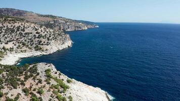 fuco volante al di sopra di roccioso costa linea con bellissimo blu in profondità mare acqua. bellissimo mare paesaggio. video