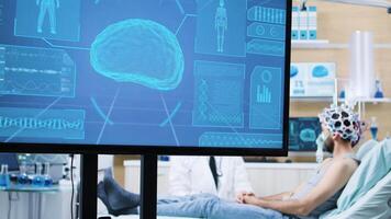 Fernseher Bildschirm im ein Neurologie Center mit Gehirn Aktivität von ein geduldig. geduldig tragen Gehirnwellen Scannen Headset. video