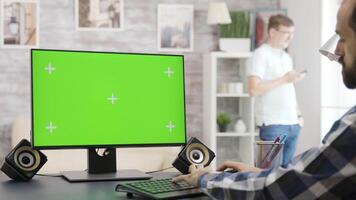 Over the shoulder shot of man working on green screen isolated mock-up display in bright and well lit room video