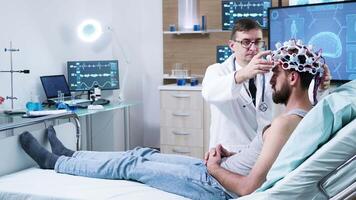 Doctor in neuroscience making adjustments to brain sensors on patient. Patient wearing brainwaves scanning headset. video