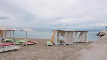 esvaziar espreguiçadeiras em pé em uma de praia de uma azul mar. fim do verão período de férias. video