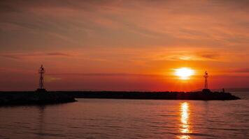 hög fyr silhuett på klippig klippa på lugna hav mot solnedgång. skön orange solnedgång. solnedgång timelapse. video