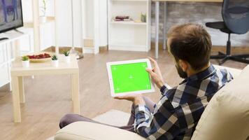 hombre participación horizontalmente un verde pantalla digital tableta ordenador personal y conmovedor eso video