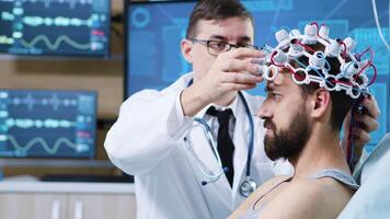 paciente preparado para cerebro escanear en moderno instalación. médico utilizando ondas cerebrales exploración auriculares en paciente. video