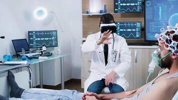 Doctor in a modern centre for brain analysis using vr headset while his patient lies in the hospital bed video