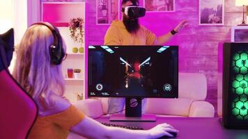 Beautiful gamer girl playing video game on powerful computer in room with neon lights