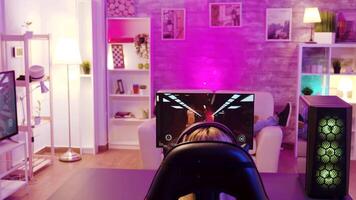 Over shoulder view of girl playing online shooter games sitting on gaming chair. Man with vr goggles in the background. video