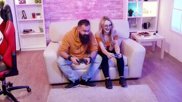 Cheerful couple making fist bump after wining at online games using wireless controllers. Gaming chair. video