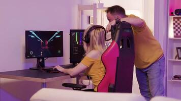 Boyfriend helping his beautiful girlfriend to win an online shooter games. Excited girlfriend playing online games. Gaming chair. video