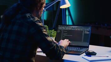 experto computadora científico escribe código en ordenador portátil pantalla mientras en vivo habitación oficina utilizando programación idiomas yo empleado eso especialista trabajando en fijación base de datos errores desde hogar, cámara un video