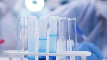 Close up of scientist adding solution with pipette on smoking blue fluid in test tubes. Chemist in research lab. video