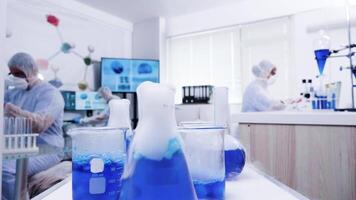 Pov of smoking blue liquid in modern science laboratory. Scientists in coverall equipment. video