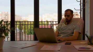 silhouette de directeur travail dans un Bureau avec gros les fenêtres allumé par chaud le coucher du soleil lumière de derrière. lent mouvement métrage video