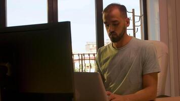 Handheld slow motion shot of manager of start up company typing on the computer in an office lit by warm sunset light video