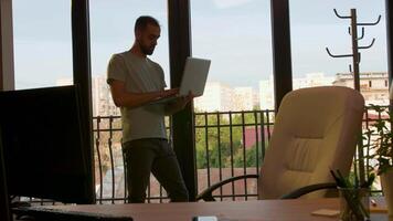 empresario trabajando cerca el ventana que tomando un sentar a su escritorio en un oficina iluminado por calentar puesta de sol ligero. Mano lento movimiento Disparo video