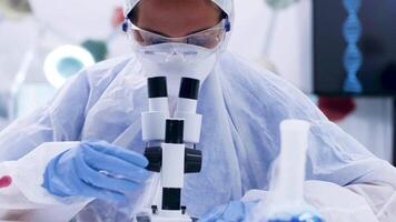 Chemist scientist doing lab research using a modern microscope. Smoking blue fluid with reagent. video