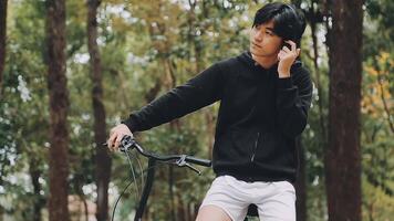 portrait de Beau souriant élégant branché lambersexuel modèle.homme habillé dans blanc T-shirt. mode Masculin équitation une bicyclette sur le rue Contexte dans des lunettes de soleil video