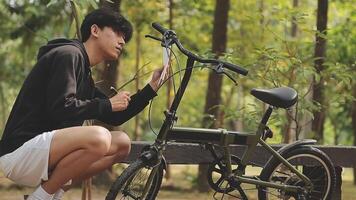 bonito à moda homem mensagens de texto em a telefone e dirigindo uma bicicleta dentro a cidade. video