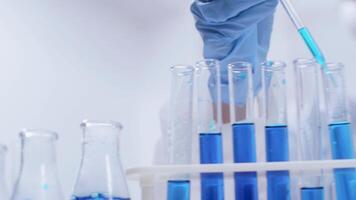 Close up handheld footage of female scientist doing scientific test with blue liquid from test tubes. Chemical reaction. video