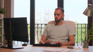 Office employee typing on computer keyboard. In background - big windows with orange sunset lights hitting from behind video