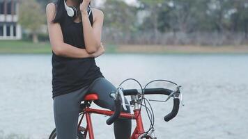 feliz jovem ásia mulher enquanto equitação uma bicicleta dentro uma cidade parque. ela sorriu usando a bicicleta do transporte. ambientalmente amigáveis conceito. video