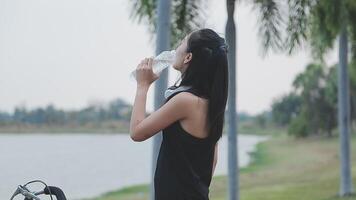 Happy young Asian woman while riding a bicycle in a city park. She smiled using the bicycle of transportation. Environmentally friendly concept. video