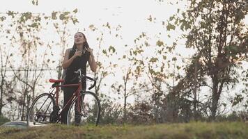 contento giovane asiatico donna mentre equitazione un' bicicletta nel un' città parco. lei sorrise utilizzando il bicicletta di trasporto. l'ambiente amichevole concetto. video