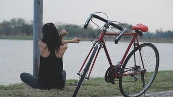 contento joven asiático mujer mientras montando un bicicleta en un ciudad parque. ella sonrió utilizando el bicicleta de transporte. ambientalmente simpático concepto. video