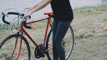 contento joven asiático mujer mientras montando un bicicleta en un ciudad parque. ella sonrió utilizando el bicicleta de transporte. ambientalmente simpático concepto. video