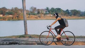 feliz jovem ásia mulher enquanto equitação uma bicicleta dentro uma cidade parque. ela sorriu usando a bicicleta do transporte. ambientalmente amigáveis conceito. video