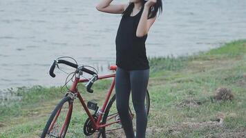 contento joven asiático mujer mientras montando un bicicleta en un ciudad parque. ella sonrió utilizando el bicicleta de transporte. ambientalmente simpático concepto. video