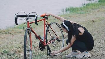 contento joven asiático mujer mientras montando un bicicleta en un ciudad parque. ella sonrió utilizando el bicicleta de transporte. ambientalmente simpático concepto. video