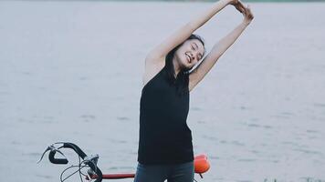 Happy young Asian woman while riding a bicycle in a city park. She smiled using the bicycle of transportation. Environmentally friendly concept. video