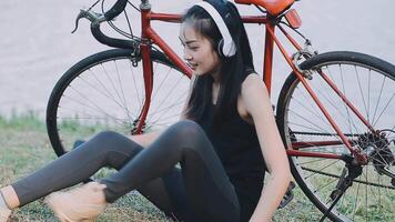 contento joven asiático mujer mientras montando un bicicleta en un ciudad parque. ella sonrió utilizando el bicicleta de transporte. ambientalmente simpático concepto. video