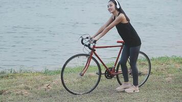 contento giovane asiatico donna mentre equitazione un' bicicletta nel un' città parco. lei sorrise utilizzando il bicicletta di trasporto. l'ambiente amichevole concetto. video