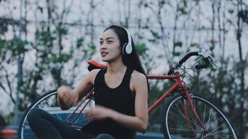 contento joven asiático mujer mientras montando un bicicleta en un ciudad parque. ella sonrió utilizando el bicicleta de transporte. ambientalmente simpático concepto. video