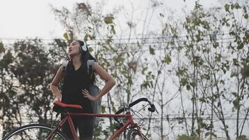 contento giovane asiatico donna mentre equitazione un' bicicletta nel un' città parco. lei sorrise utilizzando il bicicletta di trasporto. l'ambiente amichevole concetto. video