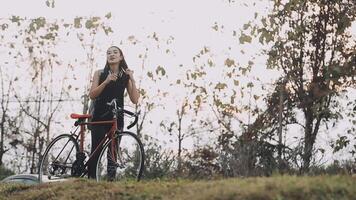 feliz jovem ásia mulher enquanto equitação uma bicicleta dentro uma cidade parque. ela sorriu usando a bicicleta do transporte. ambientalmente amigáveis conceito. video