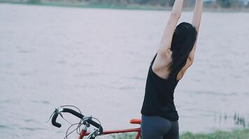 contento giovane asiatico donna mentre equitazione un' bicicletta nel un' città parco. lei sorrise utilizzando il bicicletta di trasporto. l'ambiente amichevole concetto. video