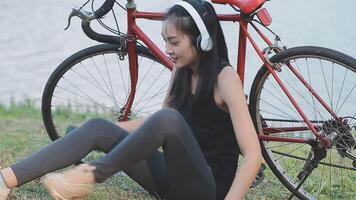 contento joven asiático mujer mientras montando un bicicleta en un ciudad parque. ella sonrió utilizando el bicicleta de transporte. ambientalmente simpático concepto. video