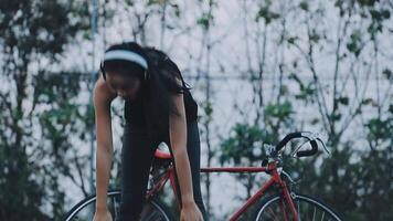 contento joven asiático mujer mientras montando un bicicleta en un ciudad parque. ella sonrió utilizando el bicicleta de transporte. ambientalmente simpático concepto. video