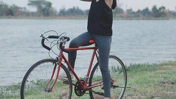 contento joven asiático mujer mientras montando un bicicleta en un ciudad parque. ella sonrió utilizando el bicicleta de transporte. ambientalmente simpático concepto. video