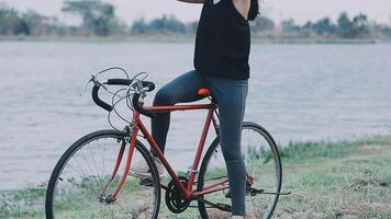 contento giovane asiatico donna mentre equitazione un' bicicletta nel un' città parco. lei sorrise utilizzando il bicicletta di trasporto. l'ambiente amichevole concetto. video