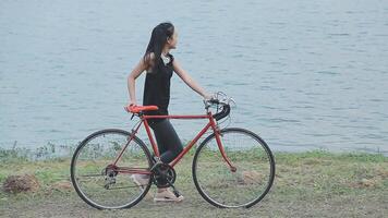 contento giovane asiatico donna mentre equitazione un' bicicletta nel un' città parco. lei sorrise utilizzando il bicicletta di trasporto. l'ambiente amichevole concetto. video